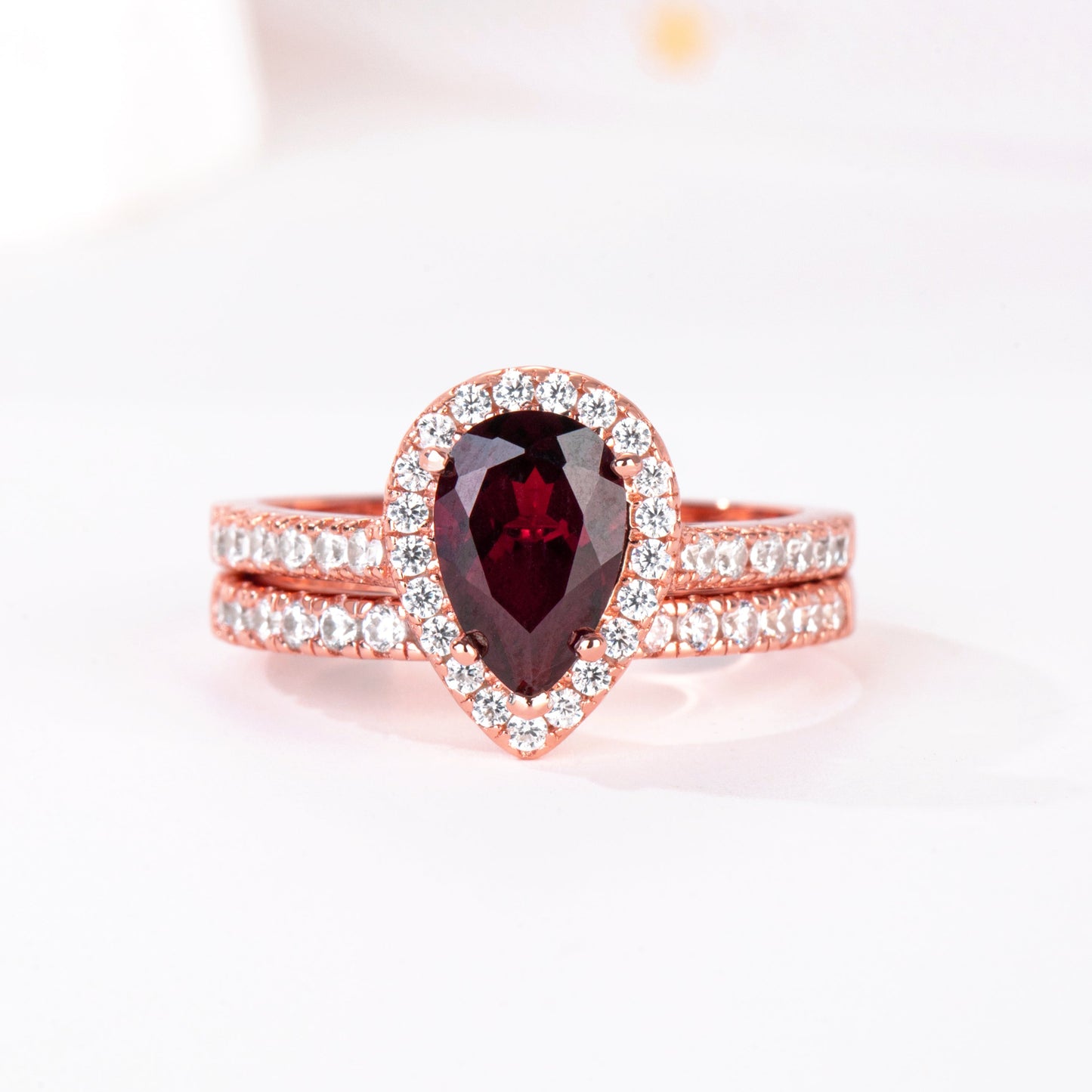 Rose gold ring with a red gemstone on a white background